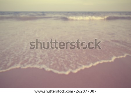 Waves on beach. In foreground frothy wave recedes over sand. Designed to work with text overlays including the text colour white. Artistic intent with filters and desaturation.