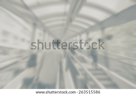 Blurred background of covered walkway with pedestrians. Designed to work with text overlays including the text colour white. Artistic intent with filters and desaturation.