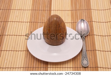 Served stone egg in a rest under egg with spoon. Close-up.