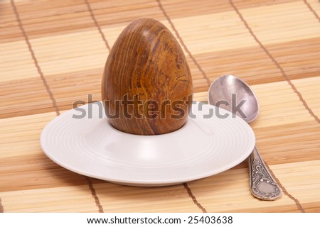 Served stone egg in a rest under egg with spoon. Close-up.