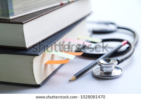 Medical student textbooks with pencil and multicolor bookmarks and stethoscope isolated on white