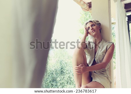 Young woman sitting by golden light in holiday villa.