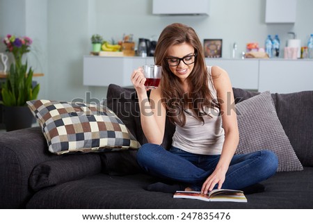 leasure and home concept - calm teenage girl woman reading book and sitting on couch at home