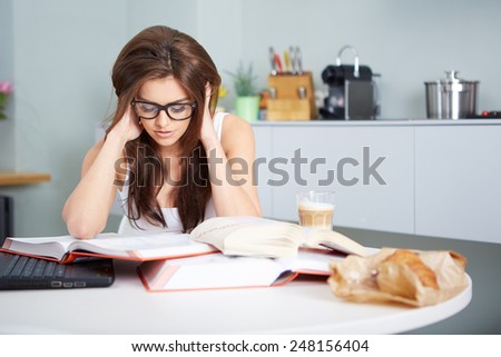 a happy young woman studying in kitchen