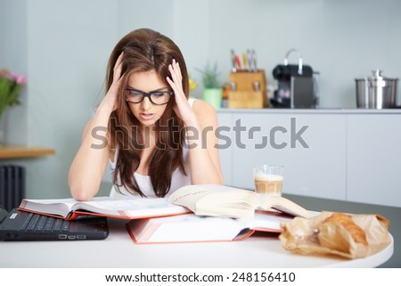 a happy young woman studying in kitchen