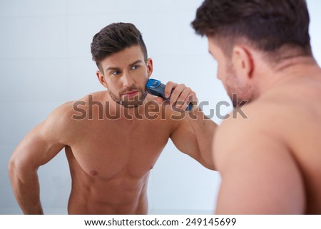 Close up portrait of young handsome man with perfect skin and hair. Shaving by electric shaver