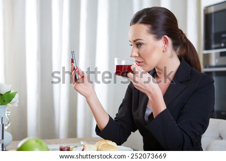 A telephoning woman with tea in kitchen