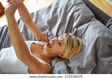 sexy young woman lying on the bed and make a selfie