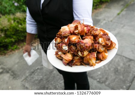 a waiter holding a plate full of bacon wrapped scallops - wedding catering series