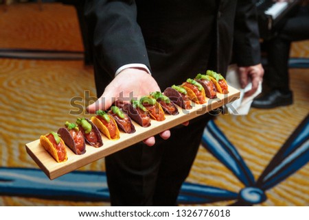 a waiter holding a wooden platter full of taco appetizers - wedding catering series
