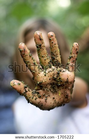 A child's hand with paint and grains of sand and dirt, in the stop position, focus on the hand, very shallow depth of field