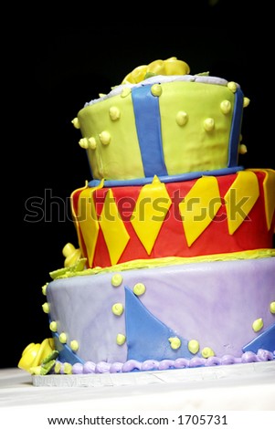 An over the top, super crazy layered wedding or party cake in mixed colors, including red, yellow, blue, purple, and green