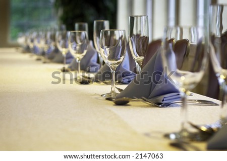 a line of wine glasses fading off in the distance, shallow depth of field. yellow linen