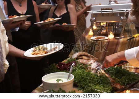 Food being served buffet style during a wedding event. This was shot with a slow shutter speed, and there is some movement noticeable.