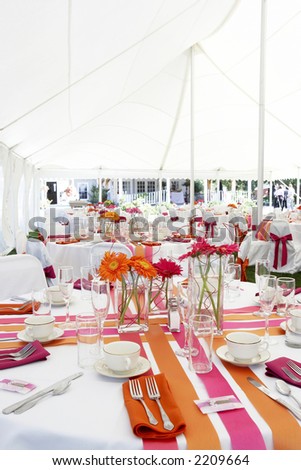 wedding tables set for fine dining during an event outside under a large white tent