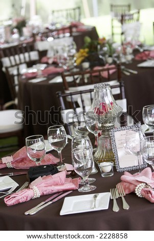 tables set for fine dining during a wedding event. Shallow depth of field, focus on items in the center of the table