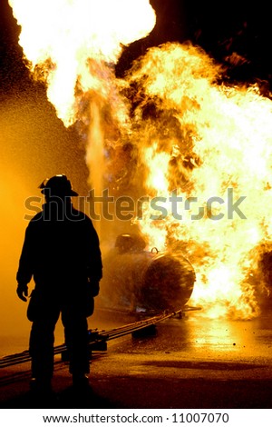 Fire fighter and burning propane tank NOTE there is slight halo caused by the intense back lighting on the fireman\'s right side and the noise isn\'t really noise it is water droplets in the air