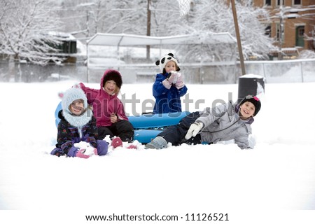 A group of kids playing in the snow outside and having fun