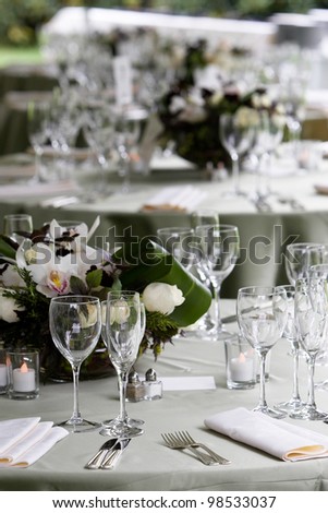 A typical dinner table setting with a very shallow depth of field with the focus on the silverware and glasses and the other tables fading out of focus