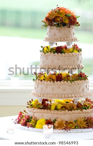 a big wedding cake built on four tiers with flowers and backlit by a window