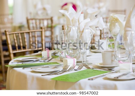 This is a wedding table set for dinner service. There are green menus on the table, but you cannot read the writing.