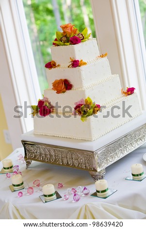 A white wedding cake with multiple layers and flowers on a silver base