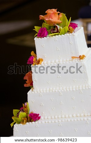 A white wedding cake with multiple layers and flowers. Wedding details.