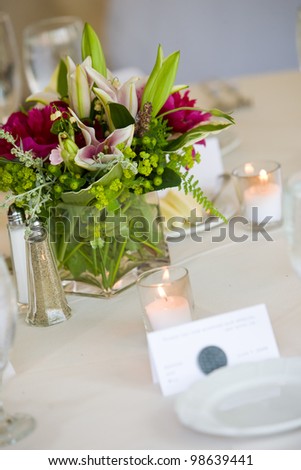 Wedding centerpiece on a table set for fine dining. Shallow depth of field, focus on the bouquet