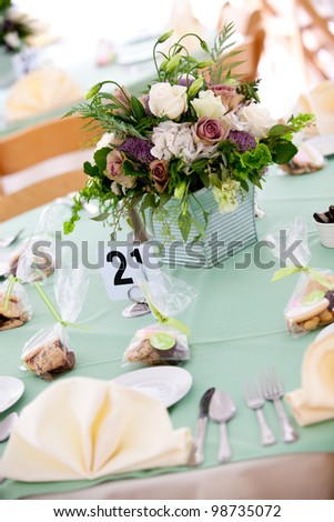 a blue wedding table with cookie favors and flower centerpiece