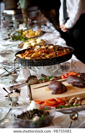 a buffet table with hot potatoes and a server in the background
