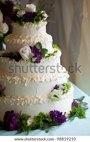 A multi level wedding cake with purple and white flowers