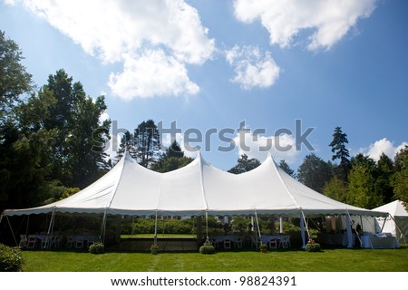 A large white wedding tent set up for an outdoor function or banquet