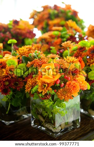 a group of wedding centerpieces in glass jars. orange and green colors