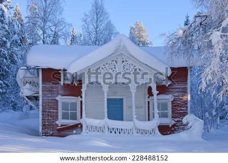 Wooden lodge with some carpentry work on the front. Newly fallen snow in the area, cold and sunny afternoon.