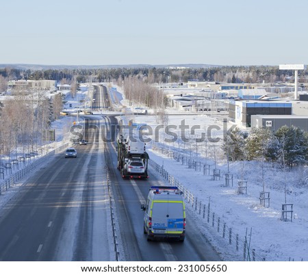 UMEA, SWEDEN ON NOVEMBER 05. Cars, vehicles, drives on a winter road on November 05, 2014 in Umea, Sweden. A sunny winter day,  frosty trees and buildings in the background.