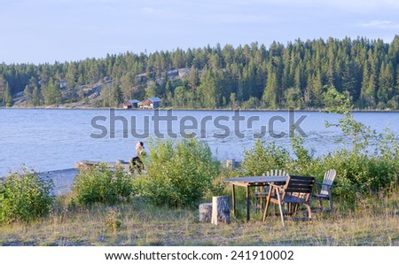 BALTIC SEA, SWEDEN ON JUNE 30. A person sits on the bridge on June 30, 2011 in The Baltic Sea, Sweden. Furniture this side in evening lit, bay in the background.