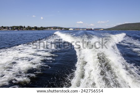 Water, prop wash in the back of high speed boat. Harbor in the background.