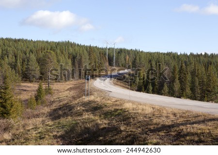 Main road through Nordic rural countryside. Lay-by and an electrical line cross the highway.