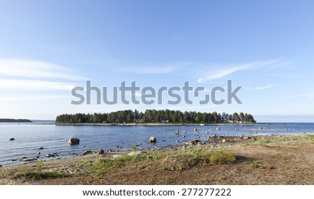 Coastline up North around Midsummer. Shore, island and buildings, cabins, lodges on the island.