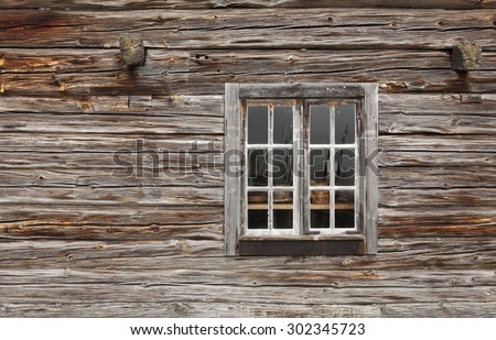 Close up on a wall of logs, timber. Windswept wooden building, window and wall at an elderly warehouse.