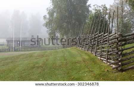 Traditional wooden fence in Nordic countries. Woodwork of bars, sticks to keep the livestock inside. Wooden buildings, left side