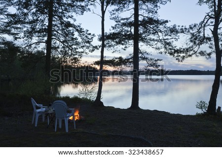 DACKESKOGEN, SWEDEN ON MAY 13. View of the Nordic night with Nordic light by a lake on May 13, 2012 in Dackeskogen, Sweden. Campfire and seats.