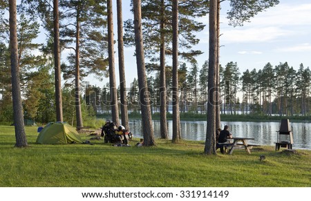 DALARNA, SWEDEN ON JULY 02. Camping in tent close to a lake on July 02, 2015 in Dalarna, Sweden. Unidentified couple on MC relax in the evening