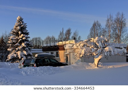 UMEA, SWEDEN ON DECEMBER 29. View of cars on a driveway, building and low sunshine on December 29, 2009 in Umea, Sweden. Newly fallen snow in the surrounding.