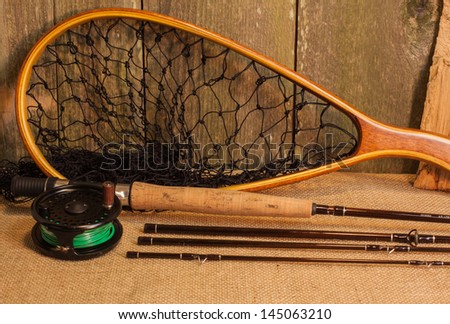 Fly fishing gear on burlap against cedar wood wall