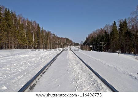 Snow-covered railway line runs through the forest