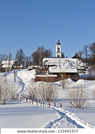 Winter country landscape, path in deep snow across the frozen creek