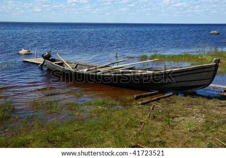 Old wooden fishing motor boat at the lake bank in northern russian village