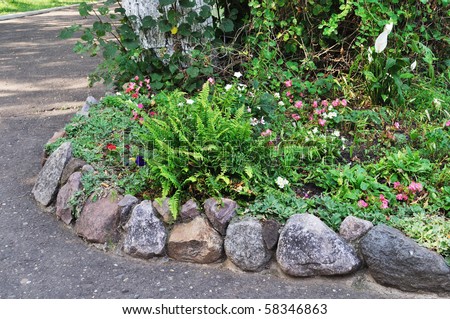 Blooming flowers in flower bed with stone border