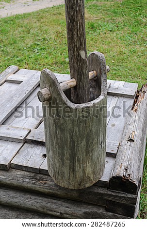 Old wooden bucket standing on the edge of the wooden well